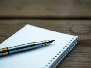 A fountain pen sitting on a pad of paper